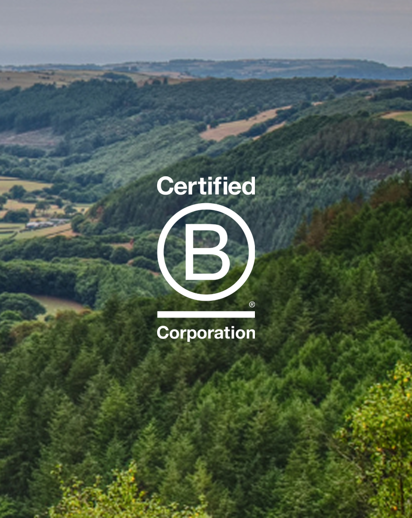 Certified B Corporation logo over a forested green valley